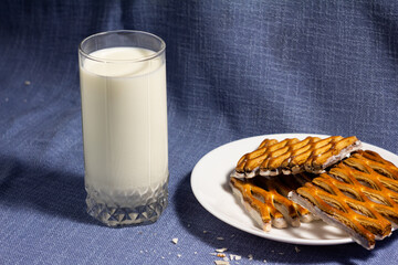 photo of a glass of milk with delicious puff pastry mesh cookies with white chocolate in a plate on a blue background