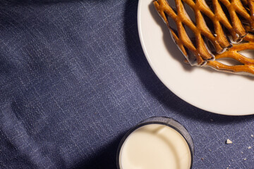 photo - a glass of fresh milk with sweet cookies from puff pastry with white chocolate - on a blue backgroun