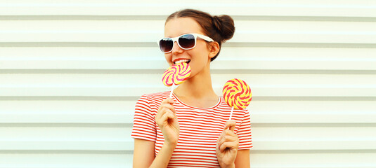 Summer portrait of happy smiling young woman with lollipop on white background