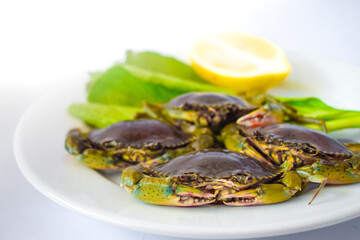 Green crab, oranges and vegetables on a white plate ready to be cooked