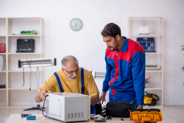 Two male repairmen working at workshop