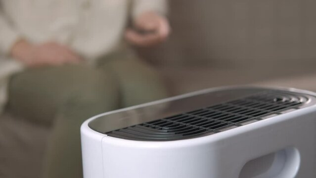 Clean air at home with digital purifier. A woman clean the air with digital air purifier in the room.