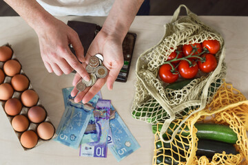 Female hands counting Canadian cash money coins and bags with fresh produce
