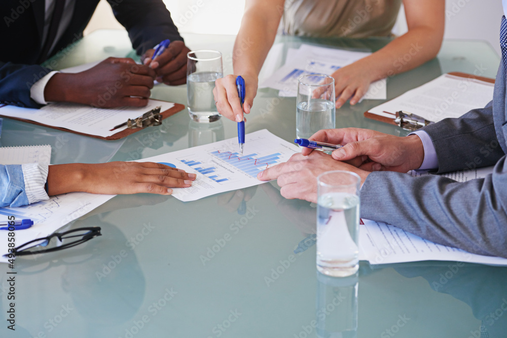 Poster taking a look at the numbers. cropped shot of a group of businesspeople discussing financial documen