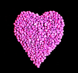 depilatory pink  hard wax beans with the shape of heart on black blank background for women in love waxing