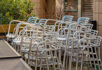 Close-up on a pile of aluminum chairs. Pile of chairs at the backyard of a street cafe.