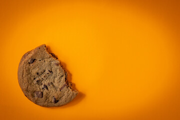 Crescent of crushed chocolate chips cookie on bright orange background
