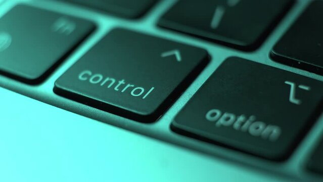 User finger presses repeatedly Control key on laptop keyboard at green light extreme closeup. Person works on computer in office. Digital device