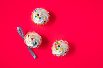 Three vanilla icing cupcakes on red background