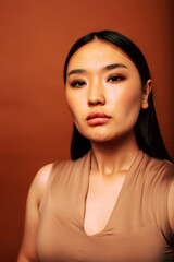 young pretty asian woman cheerful smiling posing on warm brown background, lifestyle people concept