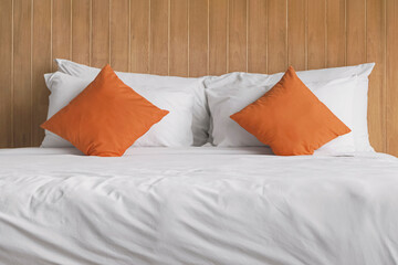 Orange pillows on a soft white bed. Bedroom and relaxation. Hotel and resort accommodation. Comfortable and luxury room.