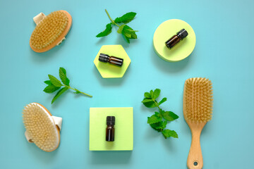 Peppermint essential oil.glass bottle and body brushes with natural bristles on green podiums...