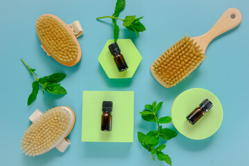 Peppermint essential oil.glass bottle and body brushes with natural bristles on green podiums.