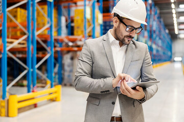 Manager scrolling on tablet and checking on orders in warehouse.