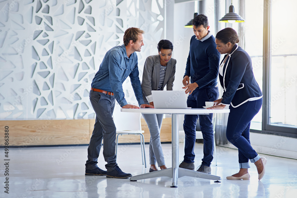 Poster putting their minds together for the project. shot of a group of coworkers working together on a lap