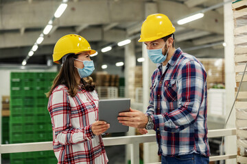 Manager showing tablet to a worker at factory.