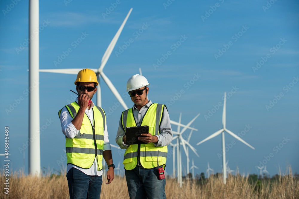 Wall mural portrait of a worker in a hardhat. two maintenance engineer in hand holding tablet and radio communi