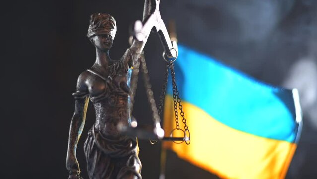 statue of justice themis on background of Ukrainian flag.War in Ukraine.Justice and trial.Struggle for justice.War with Russia.Trial over Russia