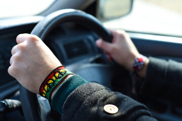Handmade DIY friendship bracelet with Rasta flag pattern with a peace symbol on wrist. Hands...