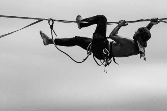 Black and white photograph of a man slacklining. Health and practice of extreme sports.