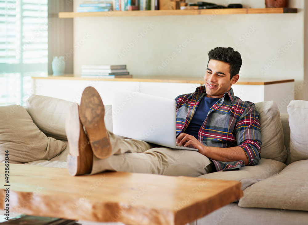 Aufkleber blogging in the comfort of home. shot of a handsome young man using his laptop while relaxing on the