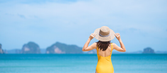 Woman tourist in yellow swimsuit and hat, happy traveler sunbathing at Paradise beach on Islands. destination, wanderlust, Asia Travel, tropical summer, vacation and holiday concept