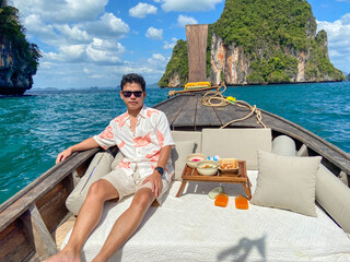 man tourist in private longtail boat trip to island with exotic food picnic, Krabi, Thailand. landmark, destination, Asia Travel, vacation, wanderlust and holiday concept