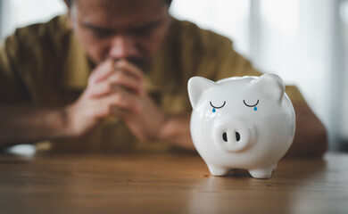 financial problems,  financial crisis, man with saves money in piggy bank at home serious thinking about something, very confused idea