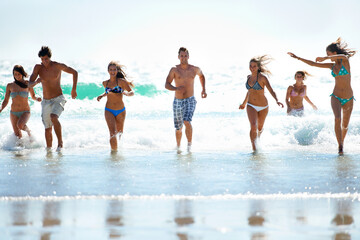 Forever young. Friends racing one another out of the ocean having fun on vacation.