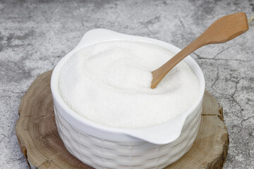 White refined sugar in a bowl with a wooden spoon. The concept of harmful unhealthy food. Glucose and diabetes mellitus. Sugar deficiency