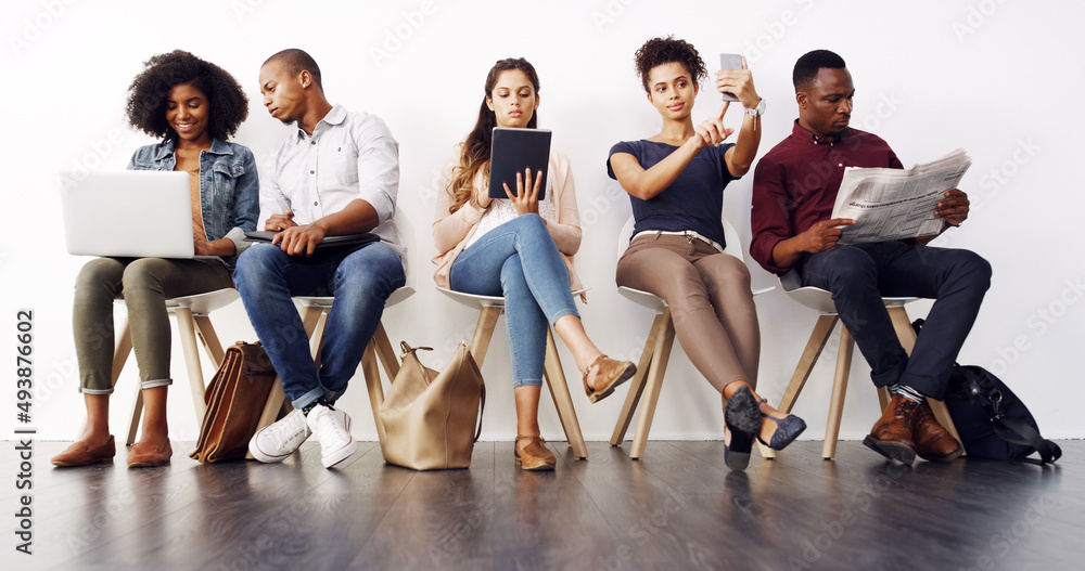 Poster doing last minute research. shot of a group of diverse businesspeople waiting in line for an intervi
