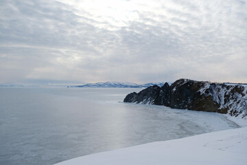 An icy river and a stone slope, with a gloomy cloudy sky.