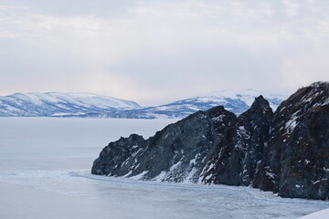 An icy river and a stone slope, with a gloomy cloudy sky.