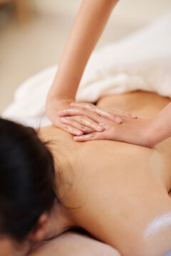 Hands of masseuse using oils when massaging back of female client