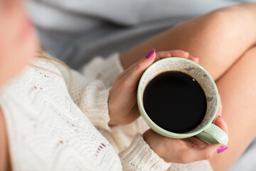 Porcelain coffee cup held by a woman's hands.