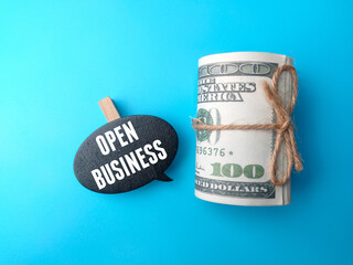Top view wooden board and banknotes with text OPEN BUSINESS on blue background.
