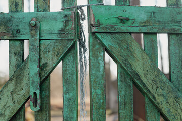 old green painted cemetery gate tied or locked with twine, Wooden background with peeling paint.
