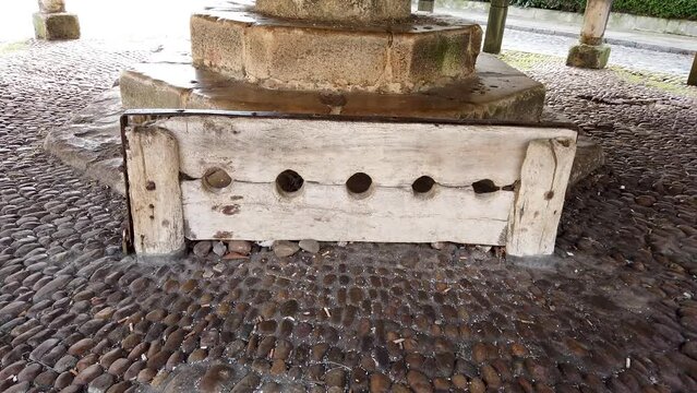 original stocks with 5 holes set in a cobbled floor underneath the Buttercross in the Market Place in the market town Oakham in the county of Rutland, England, United Kingdom. This is a Grade 1 site