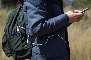 Man holds a smartphone in his hands and charges it with black power bank against the backdrop of a...
