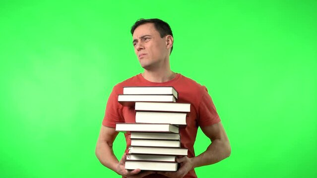 Exhausted man carrying pile of textbooks exhaling during exam preparation