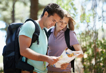 PLanning their route. A young couple studying their map while hiking through the woods.