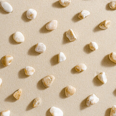 Fototapeta na wymiar Pattern with close up pebble sea stones on sand texture. Layout from natural stone neutral natural tones. Minimal style sandy background