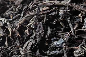 Dried black tea leaves as background.