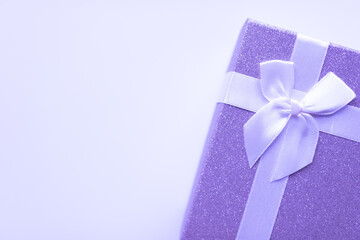beautiful gift for spring holidays - a purple box with a white bow on a white isolated background with copyspace, shining with sparkles. spring holidays and celebrations congratulations concept