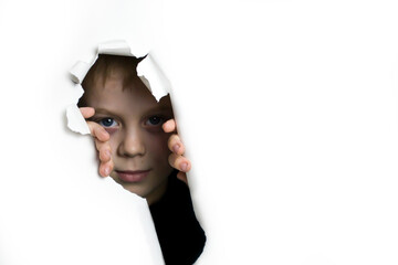 A boy peeks out of a hole on a white background.