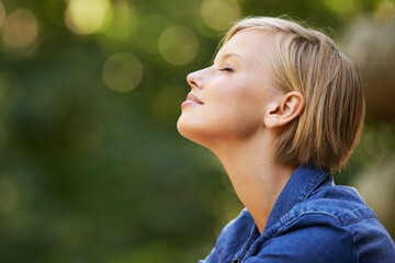 Taking it all in. A young woman outdoors with her eyes closed beside copyspace.