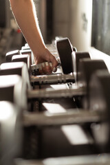 Fototapeta na wymiar female hand takes a dumbbell in the gym. sport and healthy lifestyle concept.