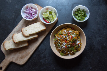 Indian street food ghugni or dried yellow peas cooked with spices served in a bowl on a dark background. Top view.