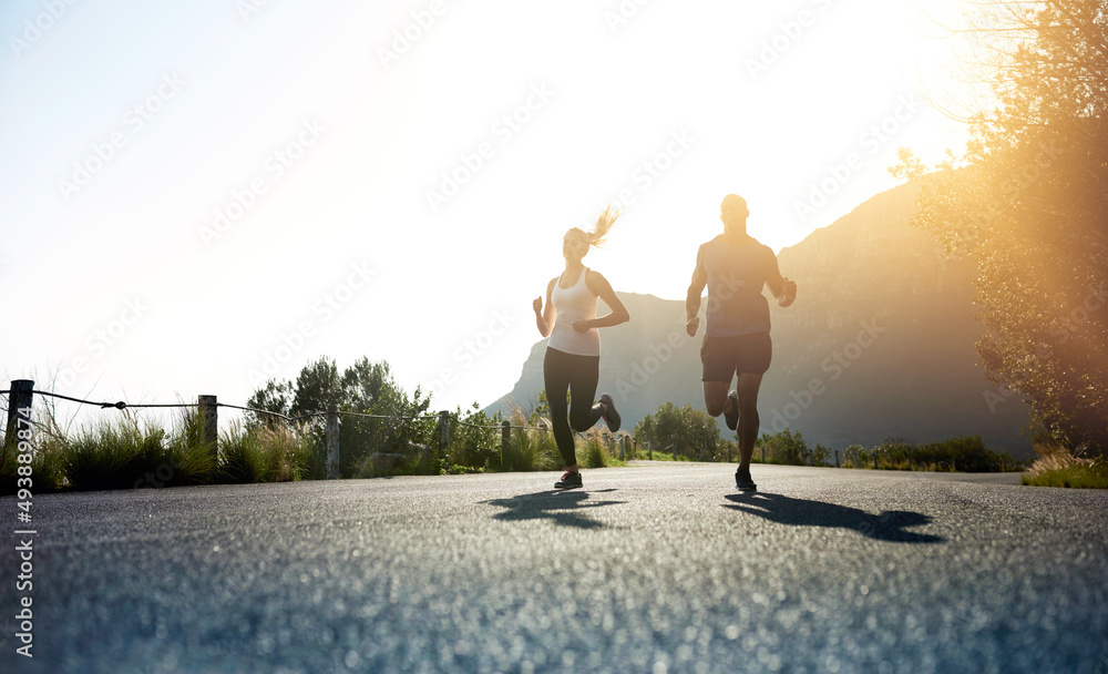Poster theres one way to succeed and thats to give everything. low angle shot of two people running on a ta