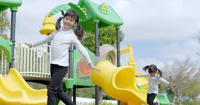 Slow motion shot, Two Asian cute girl slowly play with extend the arms and smile with happy together at playground